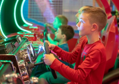 Three boys playing racing arcade games